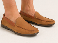 Brown loafers worn by a person on a light gray background